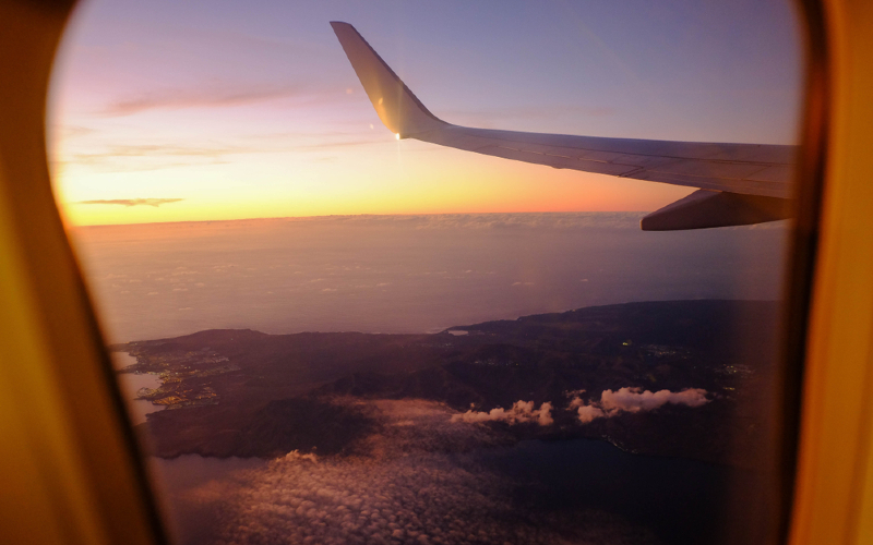 kijkje uit vliegtuigraam op de vleugel en zonsondergang