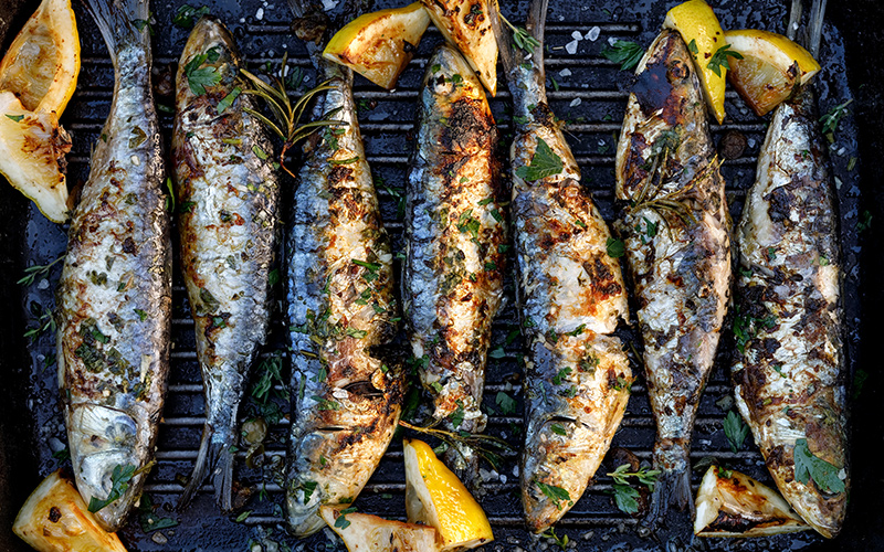 Zeven sardines naast elkaar, op houtskool gegrild