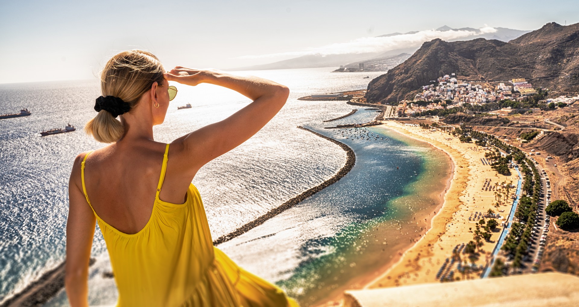 Vrouw kijkt uit over strand op een warme dag op Tenerife