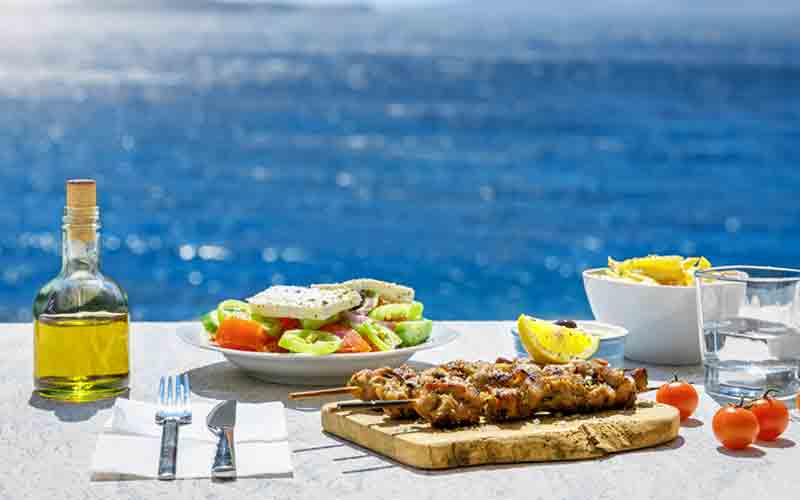 gedekte tafel met gyros en griekse salade met uitzicht op zee 