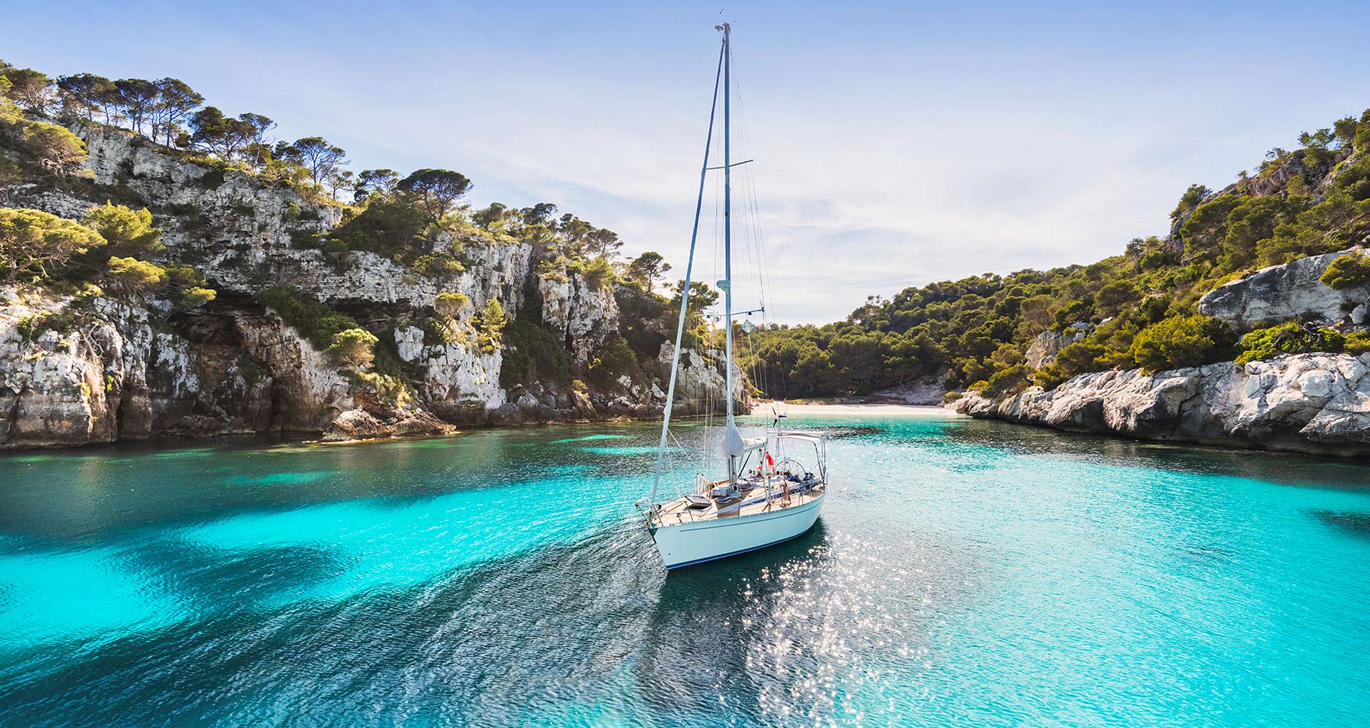 Baai in Ibiza waar een zeilboot vaart