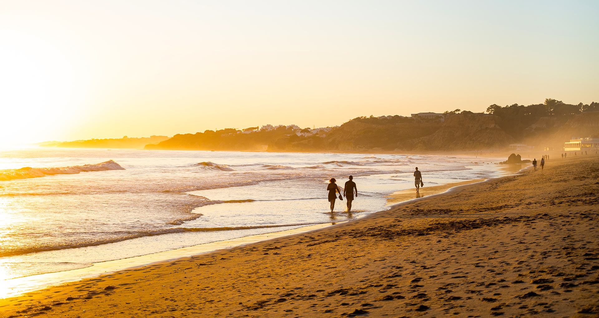 Drie mensen die langs de kust van Falesia Beach lopen