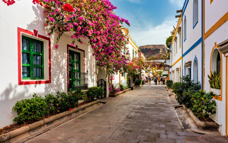 een straatje met witte huisjes en bloemen aan de gevels in puerto de mogan