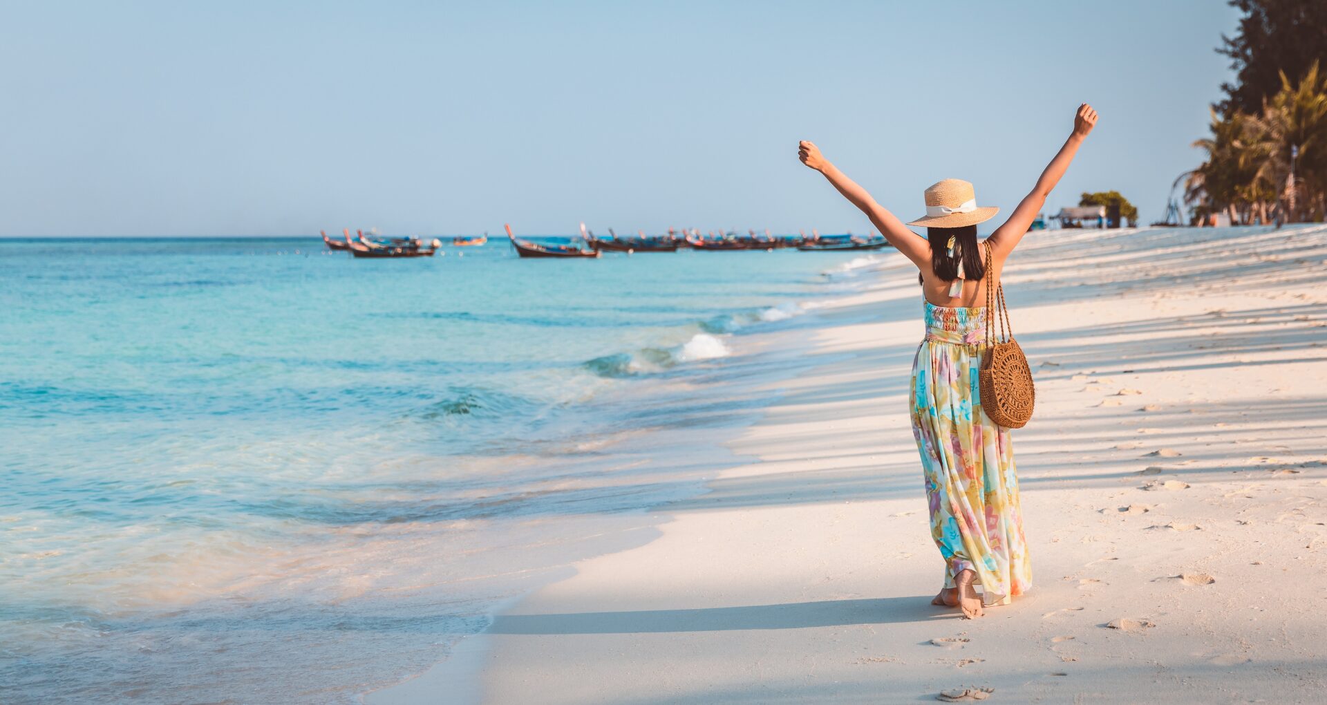 vrouw met juichende armen in de lucht, alleen op tropisch wit strand met helderblauwe zee