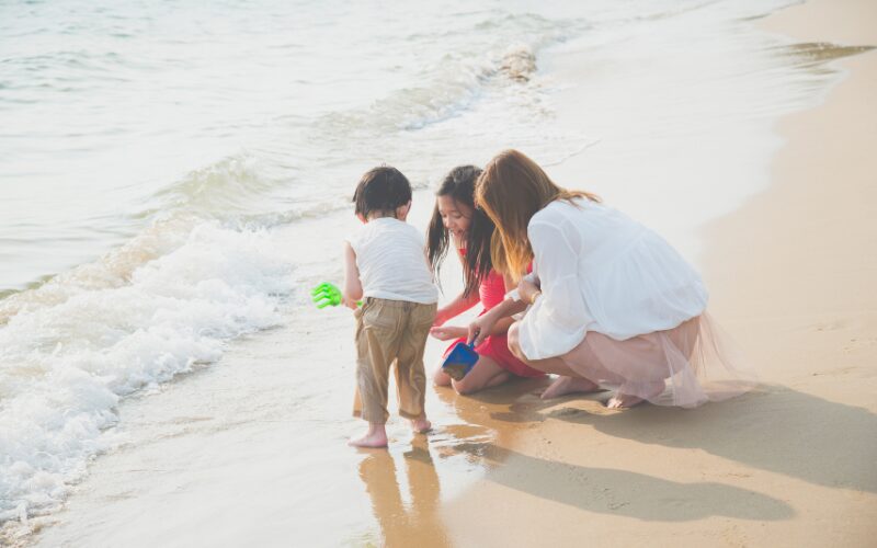 moeder speelt met 2 kindjes op het strand in de branding