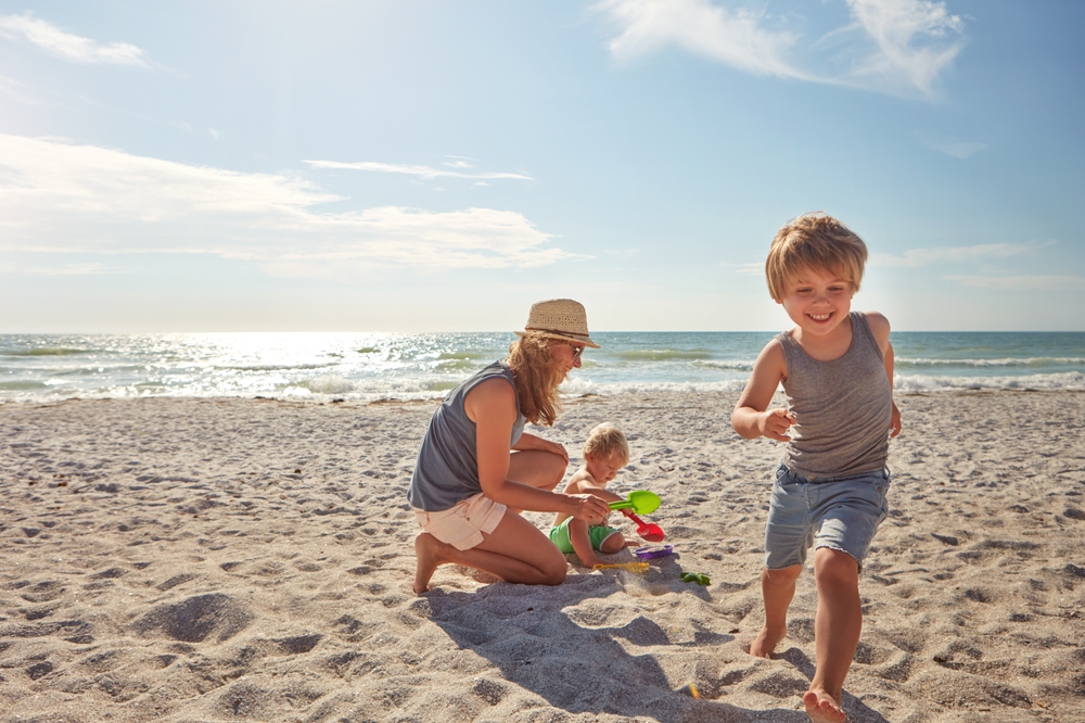 Foto: moeder geniet samen met haar kinderen op het strand