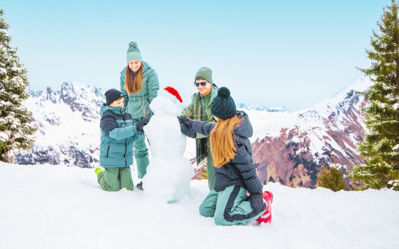 Familie bouwt sneeuwpop.